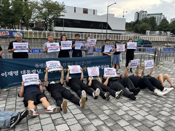 [서울=뉴시스] 서지수 인턴기자 = 1일 서울 용산 대통령실 앞에서 열린 온라인 플랫폼법 제정 촉구 기자회견에서 시민사회단체 회원들이 바닥에 누워 수수료 인상과 약관 불공정 문제를 규탄하는 퍼포먼스를 하고 있다. 2025.09.01. photo@newsis.com *재판매 및 DB 금지