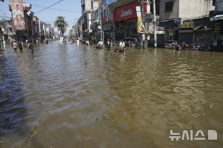 [AP/뉴시스] 4일 파키스탄 구즈라트 주민들이 물이 차오른 길을 어렵게 헤처가고 있다