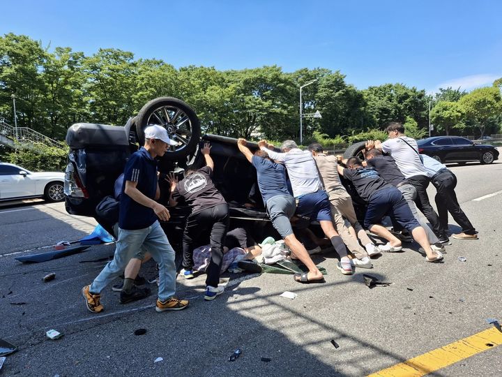 [안산=뉴시스]8월2일 안산시 상록구 부곡동 육교 인근에서 시민들이 전복된 차량을 밀어 올리고 있다.(사진=안산시 제공)2025.09.04.photo@newsis.com *재판매 및 DB 금지