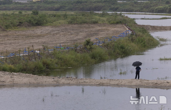 [강릉=뉴시스] 김근수 기자 = 극심한 가뭄이 이어진 지난해 9월 4일 강원 강릉시 연곡면의 한 취수장에서 직원이 우산을 쓰고 하천을 바라보고 있는 모습. 2025.09.04. ks@newsis.com