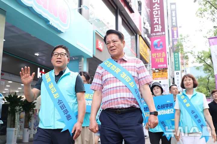 [안양=뉴시스] 최대호 시장(분홍색 체크무늬 상의)이 관내 평촌 1번가 상인회 회원들과 소비 쿠폰 사용 촉진 캠페인을 하고 있다. (사진=안양시 제공).2025.09.05.photo@newsis.com