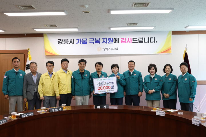 박미옥 경산시의회 산업건설위원장(오른쪽서 5번째)과 최익순 강릉시의회 의장이 음용수 지원 카드를 들고 포즈를 취하고 있다. (사진=경산시의회 제공) *재판매 및 DB 금지