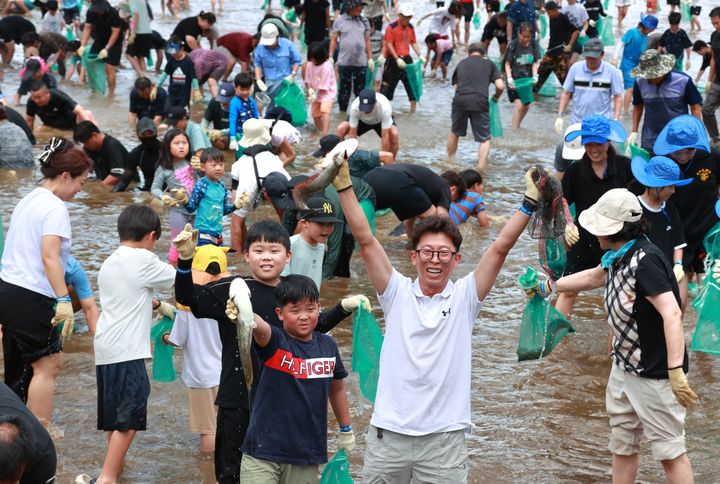 [괴산=뉴시스] 서주영 기자 = 6일 충북 괴산군의 동진천에서 열린 2025 괴산고추축제 프로그램 '고추물고기를 잡아라'의 한 참가자가 잡은 물고기를 들고 웃음을 짓고 있다. (사진= 괴산군 제공) 2025.09.06. photo@newsis.com
