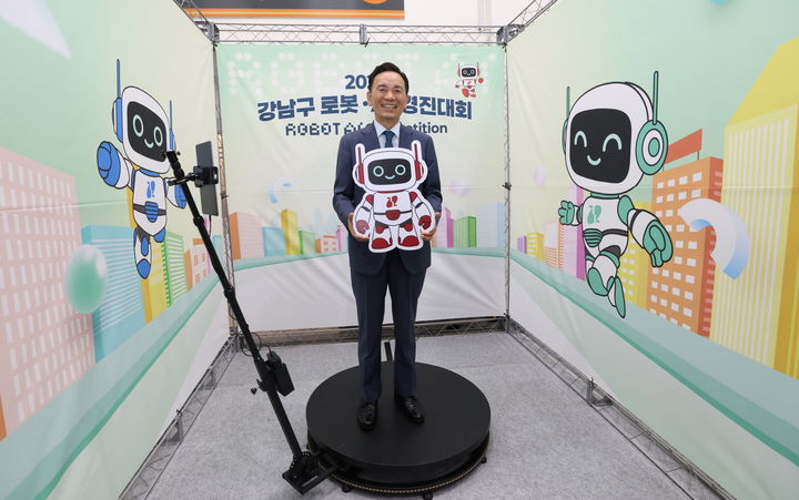 [서울=뉴시스] ‘2025 강남구 로봇·AI 경진대회’가 열린 서울 SETEC 행사장 내 체험존에서 조성명 강남구청장이 360도 비디오 포토부스를 체험하며 마스코트와 함께 기념 촬영을 하고 있다. 2025.09.07. (사진=강남구 제공) *재판매 및 DB 금지