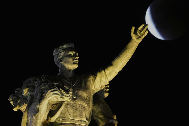 [모스크바=AP/뉴시스] 7일(현지 시간) 러시아 모스크바의 국립경제성과전시센터(VDNKh) 중앙 전시관 조형물 상공에서 개기월식이 진행되고 있다. '개기월식'은 달이 지구 그림자에 완전히 가려지는 천문 현상이다. 2025.09.08. 