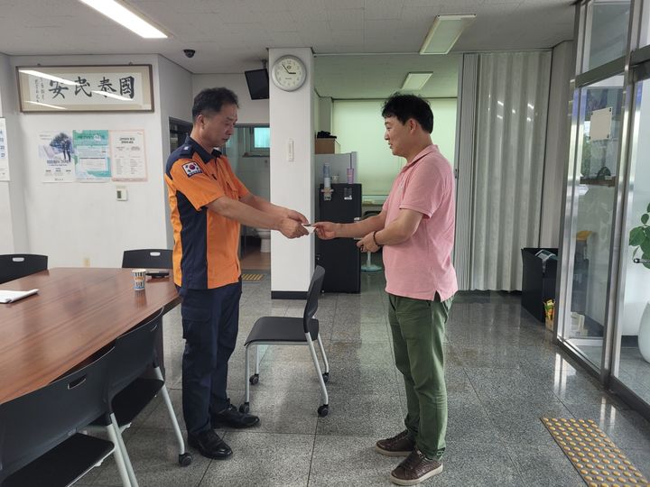 [창녕=뉴시스] 창녕소방서 영산 119안전센터 배승한 센터장이 길에서 발견한 창녕사랑상품권이 든 봉투를 습득해 주인에게 돌려주고 있다. (사진= 창녕소방서 제공) 2025.09.08. photo@newsis.com *재판매 및 DB 금지