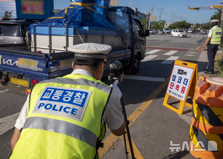 [전주=뉴시스] 강경호 기자 = 11일 오전 전북 전주시 완산구 효자동의 한 사거리에서 진행된 경찰의 '5대 반칙운전' 집중 단속 현장에서 경찰이 캠코더를 통해 교통법규 위반 여부를 촬영하고 있다. 2025.09.11. lukekang@newsis.com
