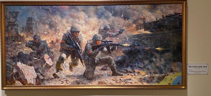 [서울=뉴시스] 9일부터 모스크바 전러시아 장식예술 박물관에서 열리고 있는 북한 미술 전시회에 전시된 우크라이나 전쟁 소재의 그림. 옆에 ‘꾸르스크지역 해방을 위하여’라는 문구가 있다.(출처: 모스크바 소식통 제공) 2025.09.12. *재판매 및 DB 금지