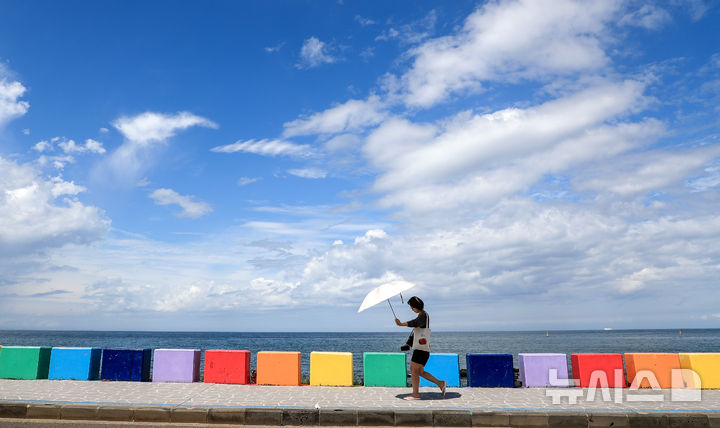 [제주=뉴시스] 우장호 기자 = 밤새 내린 비가 그치고 맑은 날씨를 보인 12일 오후 제주시 도두동 무지개 해안도로를 찾은 외국인 관광객들이 늦더위에 우산을 펼친 채 걸어가고 있다. 2025.09.12. woo1223@newsis.com