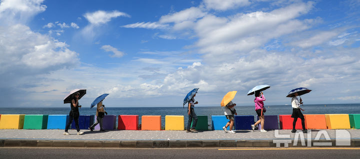 [제주=뉴시스] 우장호 기자 = 밤새 내린 비가 그치고 맑은 날씨를 보인 12일 오후 제주시 도두동 무지개 해안도로를 찾은 외국인 관광객들이 늦더위에 우산을 펼친 채 걸어가고 있다. 2025.09.12. woo1223@newsis.com