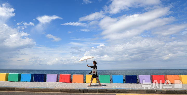 [제주=뉴시스] 우장호 기자 = 밤새 내린 비가 그치고 맑은 날씨를 보인 12일 오후 제주시 도두동 무지개 해안도로를 찾은 외국인 관광객들이 늦더위에 우산을 펼친 채 걸어가고 있다. 2025.09.12. woo1223@newsis.com