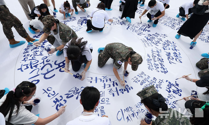 [서울=뉴시스] 김선웅 기자 = 14일 서울 용산구 전쟁기념관 평화의 광장에서 국민·국군장병(총 77명)들이 10월 1일 국군의 날 77주년을 맞아 국군의 날 브랜드 캘리그라피를 제작하고 있다.  이날 제작된 캘리그라피는 국군의 날(10월 1일)을 시각적으로 상징하고 문화적 가치를 부여하기 위해 제작됐으며 완성된 작품은 정부서울청사, 전쟁기념관 외벽에 대형 현수막으로 게시될 예정이다. 2025.09.14. mangusta@newsis.com