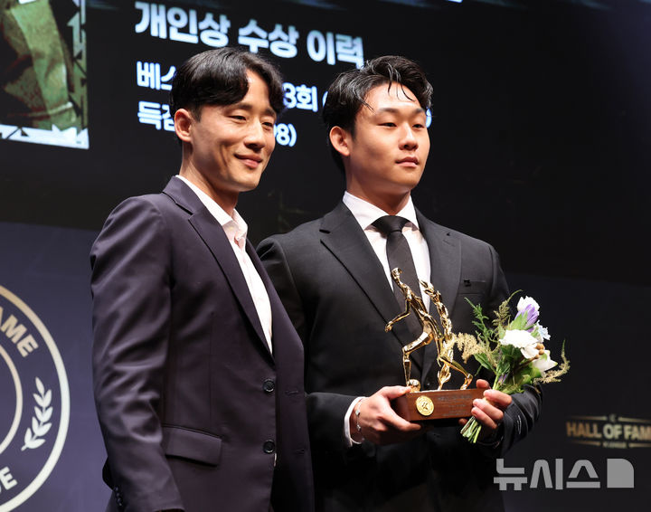[서울=뉴시스] 배훈식 기자 = 故 유상철의 아들 유선우씨가 16일 오전 서울 종로구 아산정책연구원에서 열린 제2회 K리그 명예의 전당 헌액식에서 선수 부문 헌액 트로피를 받고 김호남 K리그 어시스트 이사와 기념촬영을 하고 있다. 2025.09.16. dahora83@newsis.com