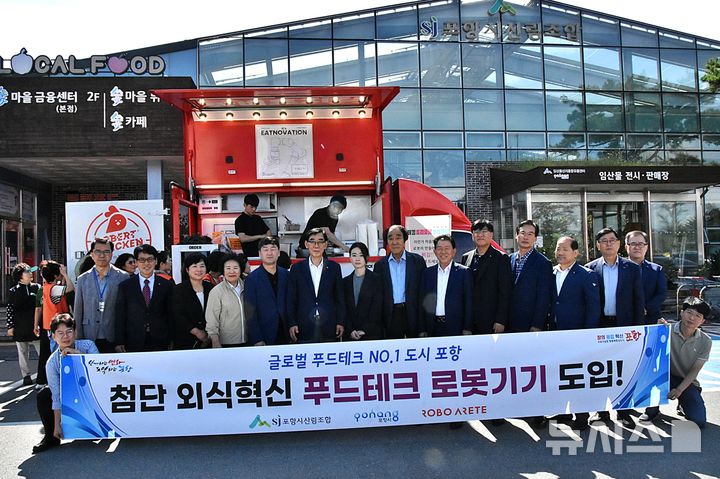 [포항=뉴시스] 송종욱 기자 = 경북 포항시가 17일 시 산림조합 앞에서 김밥말이·튀김 로봇 등으로 조리 자동화 기술을 시연하고, 시식 체험 등으로 푸드테크 도입 기념 행사를 했다. 사진은 기념 행사에서 참석자들이 기념 촬영하는 모습. (사진=포항시 제공) 2025.09.17. photo@newsis.com
