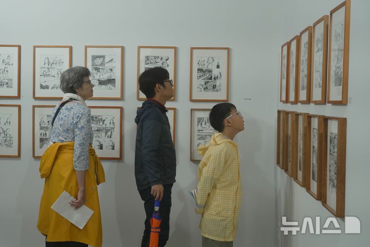 [태백=뉴시스]태백 장성마을 주민들이 아이리스PC방 건물 지하에 전시된 전지 작가의 '불확실한 내 이야기를 들어줄 한 사람이 필요해' 만화 원화를 관람하고 있다. (사진=탄탄마을협동조합 제) 