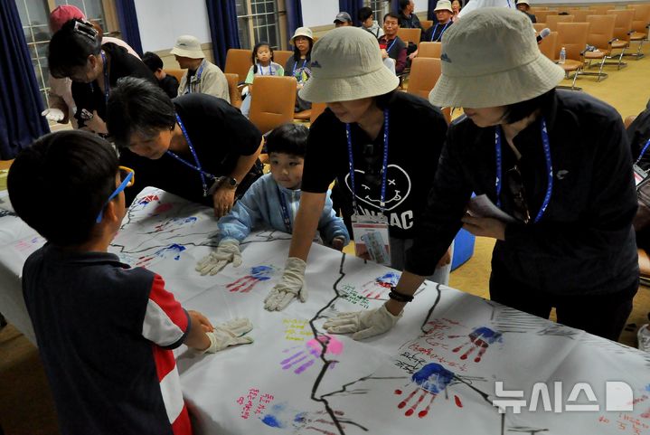 [울릉도=뉴시스] 한국해양재단(이사장 문해남)이 주관하고, 해양수산부(장관 전재수)와 민영뉴스통신사 뉴시스(사장 염영남)가 후원하는 '2025 독도탐방' 참가자들이 초대형 독도기에 손도장을 찍고 있는 모습.