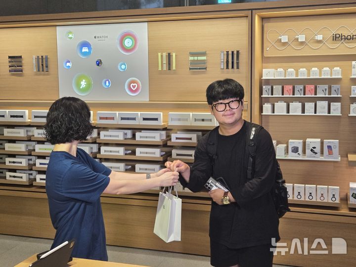 [서울=뉴시스]19일 애플 명동의 아이폰17 시리즈 1호 구매자인 김지민(20대) 씨가 애플스토어 직원에게 새로 구매한 아이폰 에어를 건네받고 있다. (사진=윤현성 기자)