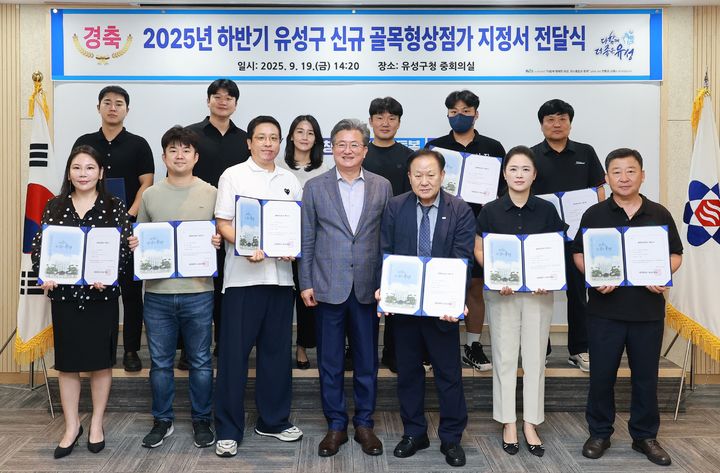 [대전=뉴시스] 조명휘 기자 = 정용래 대전 유성구청장이 19일 하반기에 신규 지정된 13개 구역의 골목형상점가에 지정서를 전달한 뒤 기념촬영을 하고 있다. (사진= 유성구 제공) 2025.09.19. photo@newsis.com *재판매 및 DB 금지