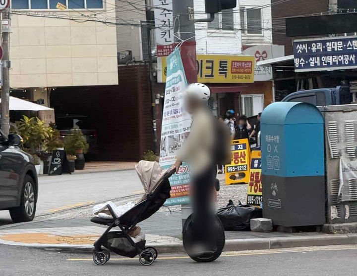 [뉴시스] 전동휠 탄 채로 유아차 끄는 남성. (사진=보배드림) *재판매 및 DB 금지