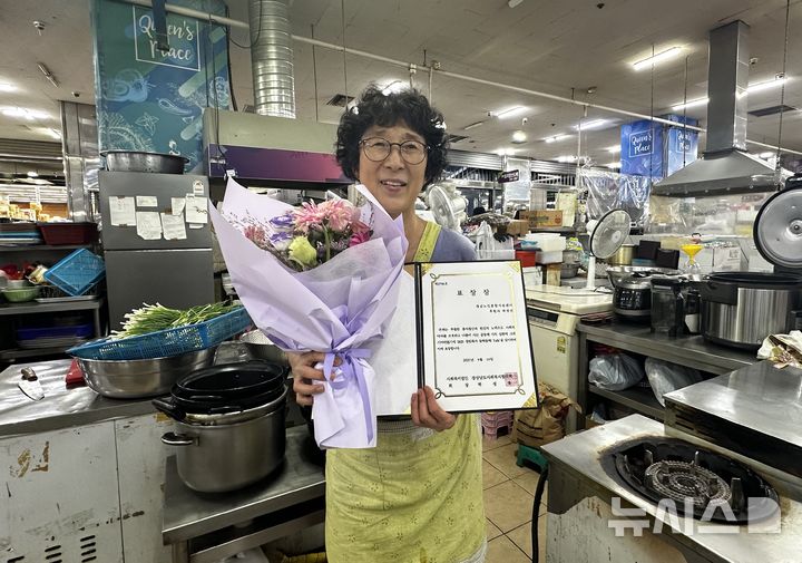 [창원=뉴시스]경남노인통합지원센터 후원자인 곽점선 즉석튀김잔치 대표가 19일 가게에서 경남사회복지협의회장상을 전달 받은 후 기념촬영하고 있다.(사진=경남노인통합지원센터 제공) 2025.09.19. photo@newsis.com