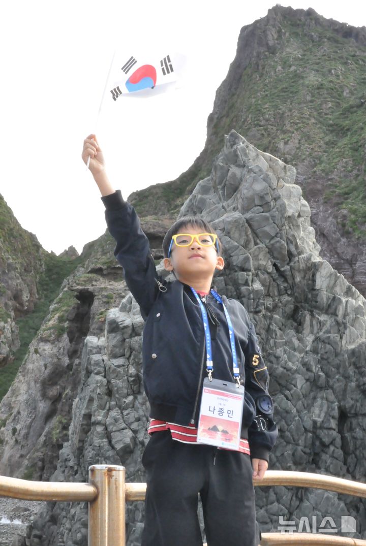 [서울=뉴시스] '2025 독도탐방' 참가자가 독도에서 태극기를 흔들고 있다. 