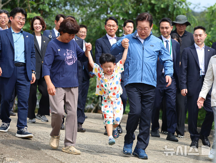 [세종=뉴시스] 고범준 기자 = 이재명 대통령이 16일 세종시 전동면 조일농원에서 박성호 조일농원 대표 가족의 손을 잡고 청년 농업인 간담회장으로 이동하고 있다. (대통령실통신사진기자단) 2025.09.16. bjko@newsis.com