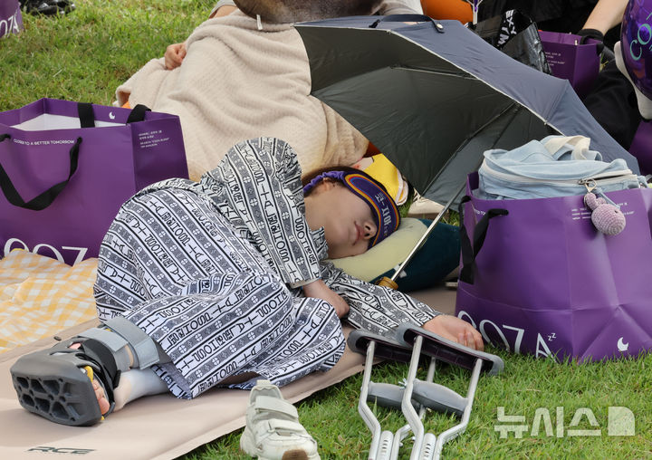 [서울=뉴시스] 배훈식 기자 = 2025 한강 잠퍼자기 대회가 열린 20일 오후 서울 여의도 한강공원에서 환자복을 입은 참가자가 낮잠을 자고 있다. 2025.09.20. dahora83@newsis.com