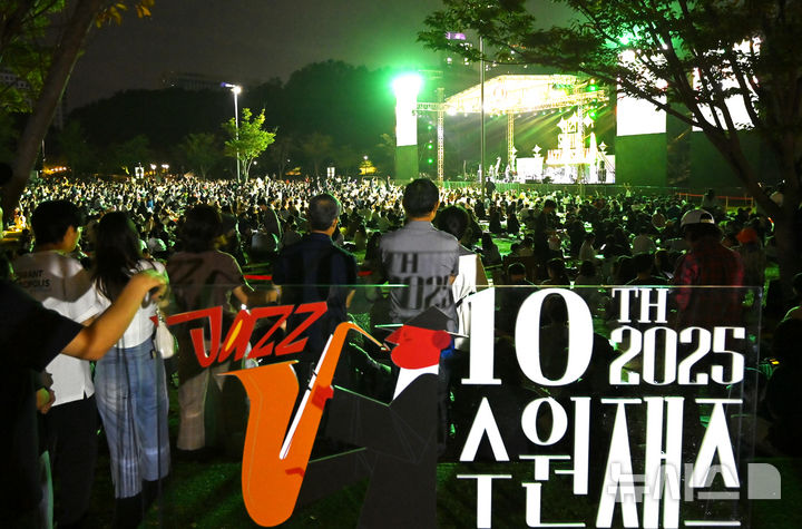 [수원=뉴시스] 김종택 기자 = 2025 수원재즈페스티벌 둘째날인 20일 오후 경기 수원시 광교호수공원 재미난 밭에서 잔디광장을 가득 메운 시민들이 선선한 가을 공기를 맞으며 흥겨운 재즈 선율을 즐기고 있다. 2025.09.20. jtk@newsis.com