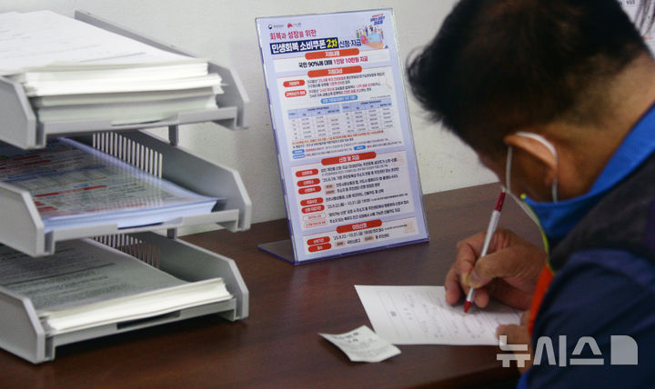 [전주=뉴시스] 김얼 기자 = 민생회복 소비쿠폰 2차 신청 첫날인 22일 전북 전주시 완산구 서신동 주민센터를 찾은 한 시민이 쿠폰을 받기 위해 신청서를 작성하고 있다. 2025.09.22. pmkeul@newsis.com