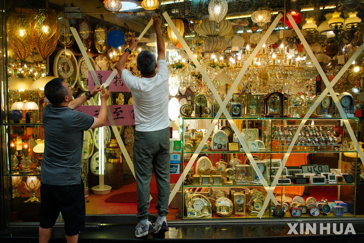 [샤먼=신화/뉴시스] 올해 가장 강력한 제18호 태풍 ‘라가사’가 24일 중국 남부 광둥성에 상륙할 것으로 예상되면서 중국 당국이 태풍·폭우 경보를 동시에 발령하고 전방위 대응에 나섰다. 사진은 22일 홍콩의 한 조명가게에서 직원들이 태풍의 피해를 막기 위해 유리창에 테이프를 붙이는 모습. 2025.09.23