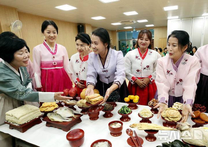 [광주=뉴시스] 지난 23일 광주 북구 운암1동 행정복지센터 다용도실에서 열린 추석 명절 '다문화가정 전통음식 체험'에서 한복을 곱게 차려 입은 다문화가정 여성들이 새마을 부녀회원들에게 절 예절과 차례상 차리는 법을 배우고 있다. (사진 = 광주 북구 제공) 2025.09.23. photo@newsis.com