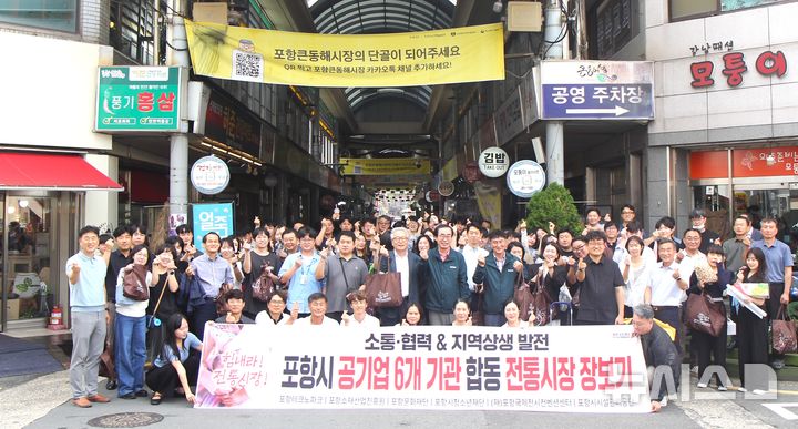 [포항=뉴시스] 포항테크노파크 등 포항시 6개 공기업 임직원 110명이 24일 큰 동해 시장에서 '추석맞이 전통 시장 장보기'를 하며 기념 촬영을 하고 있다. (사진=포항시 제공) 2025.09.24. photo@newsis.com