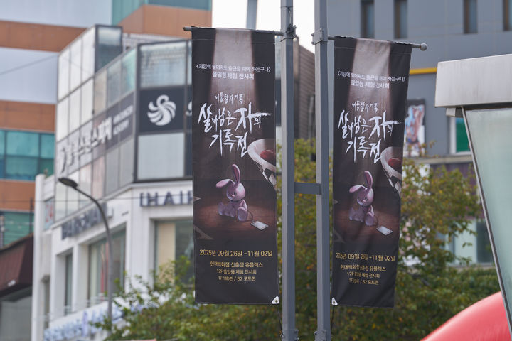 [서울=뉴시스]권민지 수습 기자 = 신촌 거리에 '괴담출근' 전시를 알리는 홍보 깃발이 걸려있다 2025.09.26. ming@newsis.com *재판매 및 DB 금지