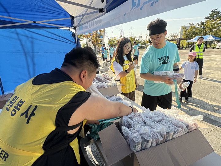 [인천=뉴시스] 신유림 기자=국내 최대 민영 뉴스통신사 뉴시스가 주최하고, 로드 스포츠가 주관하며, 인천광역시 중구청과 대한체육회가 후원하는 '제 1회 뉴시스 바다 마라톤'의 '자원봉사자 한영석 씨가 27일 인천광역시 영종도 하늘구름광장에서 펼쳐진 대회에 참석해 참가들에게 메달과 간식을 나눠주고 있다. 2025.09.27. spicy@newsis.com *재판매 및 DB 금지