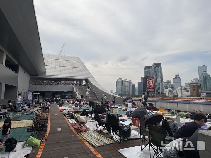 [서울=뉴시스]최은수 기자=2025 서울세계불꽃축제가 열린 27일 오후, 서울 동작구 노량진수산시장 3층 옥외 데크. 여의도 63빌딩을 정면으로 조망할 수 있는 이곳에서 시민들이 돗자리를 펴고 불꽃놀이를 기다리고 있다. 2025.09.27