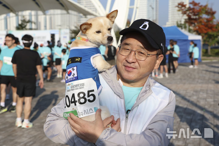 [서울=뉴시스] 조성우 기자 = 마라톤 참가자 차영종(60, 김포 통진읍)씨가 27일 인천 중구 씨사이드파크 하늘구름광장에서 열린 제1회 뉴시스 바다마라톤 대회에서 출발 전 참가견 차모찌와 함께 기념촬영을 하고 있다. 2025.09.27. xconfind@newsis.com