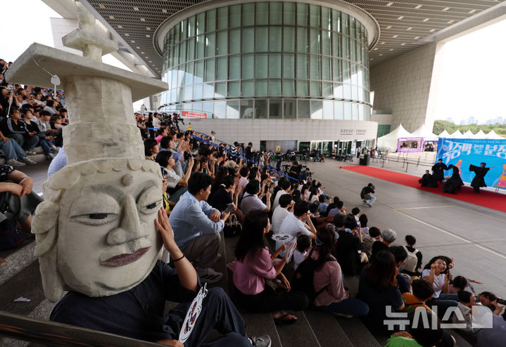 [서울=뉴시스] 이영환 기자 = 27일 오후 서울 용산구 국립중앙박물관에서 열린 2025 국중박 분장대회에서 못생긴 불상으로 알려진 은진미륵 분장을 한 시민이 케이팝 데몬 헌터스의 사자 보이즈 분장을 한 인플루언서의 공연을 관람하고 있다. 2025.09.27. 20hwan@newsis.com