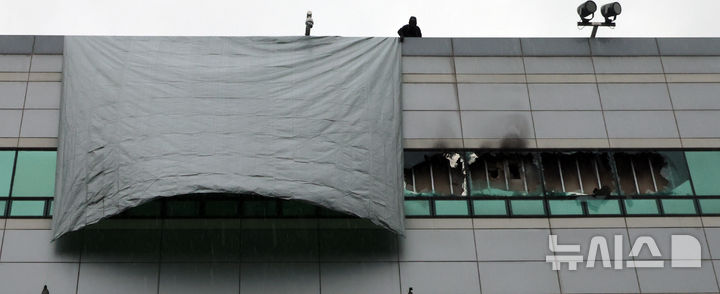 [대전=뉴시스] 강종민 기자 = 28일 화재가 완진된 대전 유성구 국가정보자원관리원에서 관계자들이 깨진 창문 위로 방수포를 덮고 있다. 2025.09.28. ppkjm@newsis.com