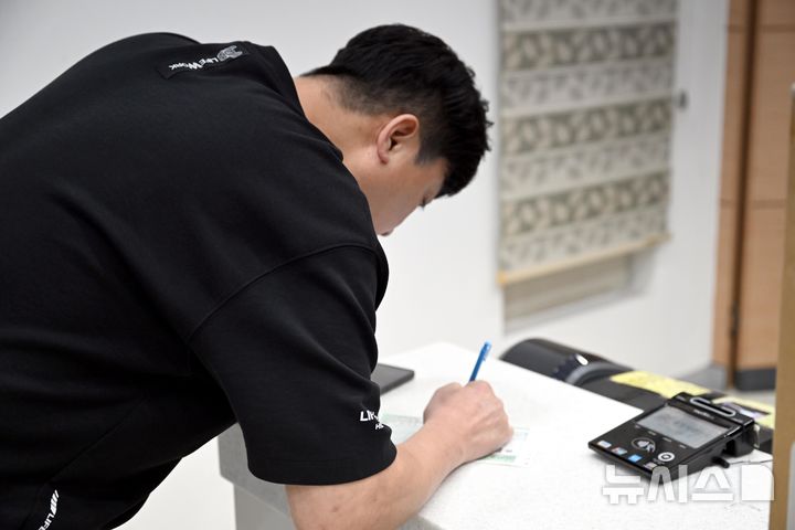 [광주=뉴시스] 국가정보자원관리원 화재로 전산망 마비 사태가 나흘째 이어지고 있는 지난 29일 오전 광주 서구 양동 광주양동금호우편취급국에서 한 시민이 배송정보가 담긴 기표지를 수기 작성하고 있다. 2025.09.29. lhh@newsis.com