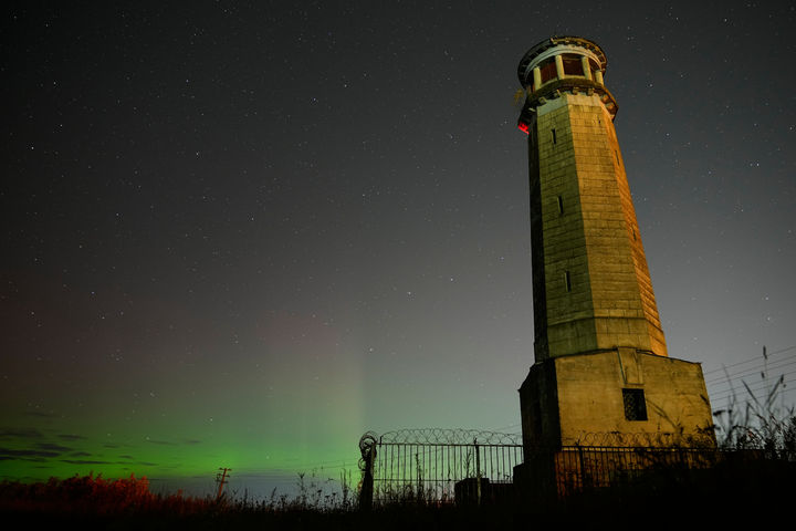 [두브나=AP/뉴시스] 30일(현지 시간) 러시아 모스크바주 볼가강 인근 도시 두브나의 모스크바 운하 둑에 있는 빅볼가 등대 인근 밤하늘에 북극광(오로라)이 관측되고 있다. 2025.09.30.
