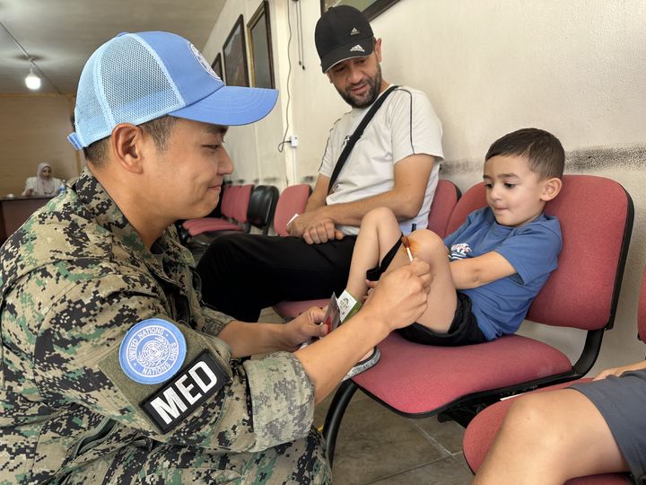 [서울=뉴시스] 동명부대 의무대 장병이 압바시아 시청에서 찾아가는 대민의료지원 간 현지 아이를 치료하고 있다. (사진=합동참모본부 제공) 2025.10.04. photo@newsis.com *재판매 및 DB 금지