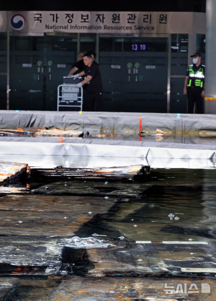 [대전=뉴시스] 김금보 기자 = 1일 오후 대전 유성구 국가정보자원관리원 화재현장에 설치된 외부 냉각 침수조의 리튬이온 배터리에서 화학작용으로 인한 기포가 올라오고 있다. 재해 복구 업체 관계자들이 컴퓨터 등 전자장비를 반출하고 있다. 2025.10.01. kgb@newsis.com