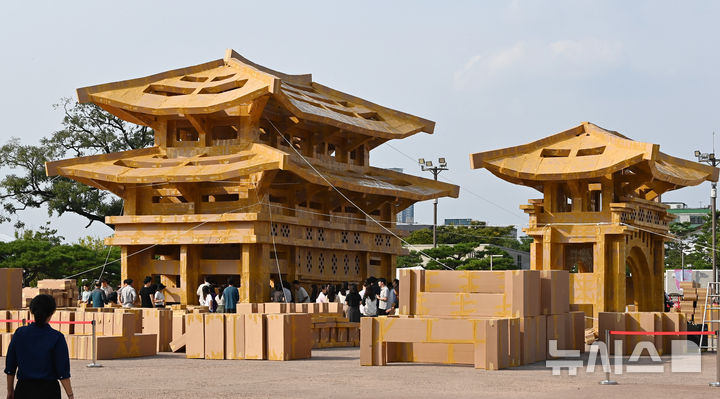 [수원=뉴시스] 김종택 기자 = 제62회 수원화성문화제가 열린 1일 경기 수원시 화성행궁 광장에서 시민들이 종이 박스로 수원화성 팔달문을 제작하고 있다. 종이박스를 자르고 조립하며 제작한 팔달문은 가로와 세로가 각각 18.68m, 13.87m에 높이는 11.73m로 실제 크기의 60% 규모다. 2025.10.01. jtk@newsis.com