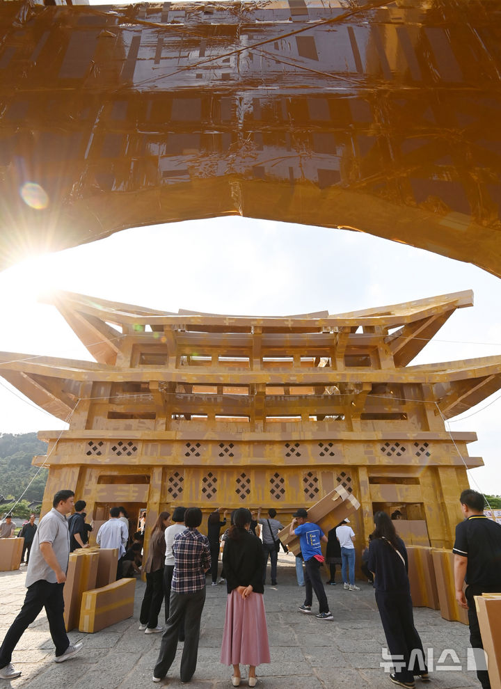 [수원=뉴시스] 김종택 기자 = 제62회 수원화성문화제가 열린 1일 경기 수원시 화성행궁 광장에서 시민들이 종이 박스로 수원화성 팔달문을 제작하고 있다. 종이박스를 자르고 조립하며 제작한 팔달문은 가로와 세로가 각각 18.68m, 13.87m에 높이는 11.73m로 실제 크기의 60% 규모다. 2025.10.01. jtk@newsis.com