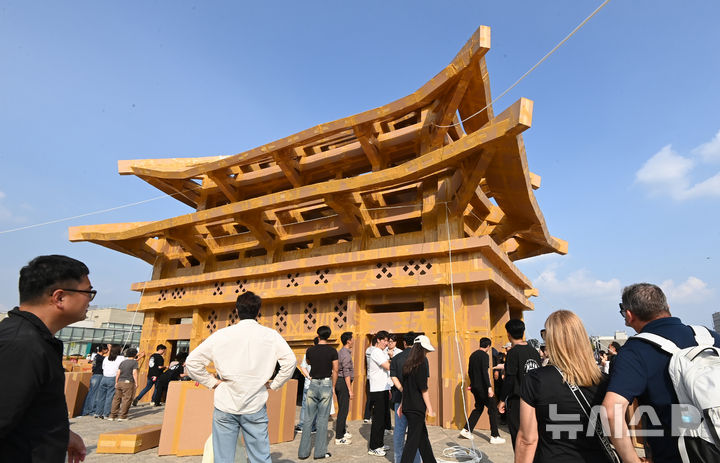 [수원=뉴시스] 김종택 기자 = 제62회 수원화성문화제가 열린 1일 경기 수원시 화성행궁 광장에서 시민들이 종이 박스로 수원화성 팔달문을 제작하고 있다. 종이박스를 자르고 조립하며 제작한 팔달문은 가로와 세로가 각각 18.68m, 13.87m에 높이는 11.73m로 실제 크기의 60% 규모다. 2025.10.01. jtk@newsis.com