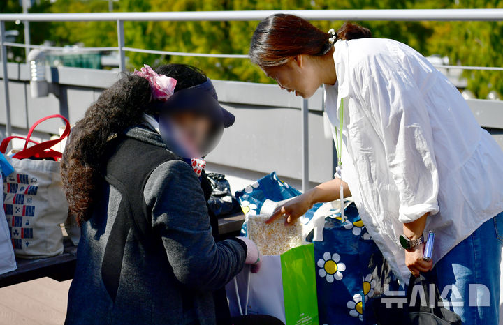 [광주=뉴시스] 김혜인 기자 = 명절을 앞둔 1일 오후 광주 서구 한 버스 터미널 인근에서 광주다시서기종합지원센터관계자가 노숙인에게 명절 먹거리 키트를 전달하고 있다. 2025.10.01. hyein0342@newsis.com