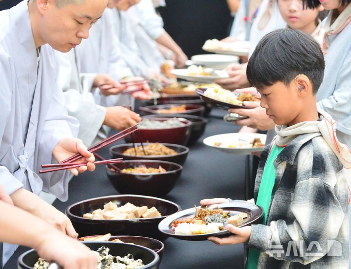 [청주=뉴시스] 서주영 기자 = 3일 충북 청주 동부창고에서 열린 강진주 작가·선재스님의 예술 퍼포먼스 '쌀의 순환-생명의 순환을 담은 한 그릇의 여정'에 참가한 어린이가 사찰 음식을 제공받고 있다. 2025.10.03. juyeong@newsis.com 