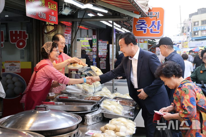[의왕=뉴시스] 김성제 시장이 추석을 앞두고 관내 도깨비시장을 찾은 가운데 한 상인과 악수를 하며 제수 등을 구매하고 있다. (사진=의왕시 제공).2025.10.04.photo@newsis.com
