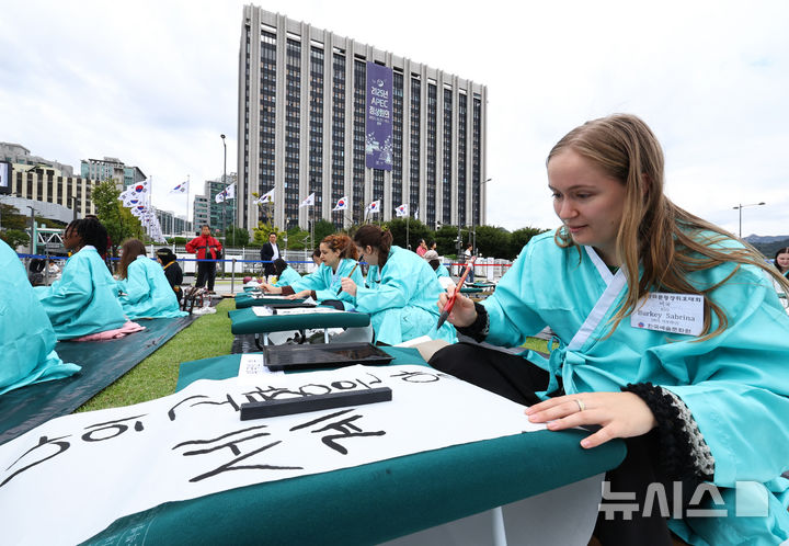 [서울=뉴시스] 최진석 기자 = 579돌 한글날인 9일 오전 서울 광화문광장에서 열린 광화문광장 휘호대회에 참가한 외국인들이 한글을 쓰고 있다. 2025.10.09. myjs@newsis.com