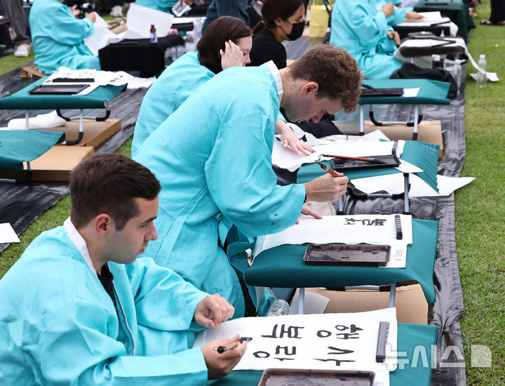 [서울=뉴시스] 최진석 기자 = 579돌 한글날인 9일 오전 서울 광화문광장에서 열린 광화문광장 휘호대회에 참가한 외국인들이 한글을 쓰고 있다. 2025.10.09. myjs@newsis.com